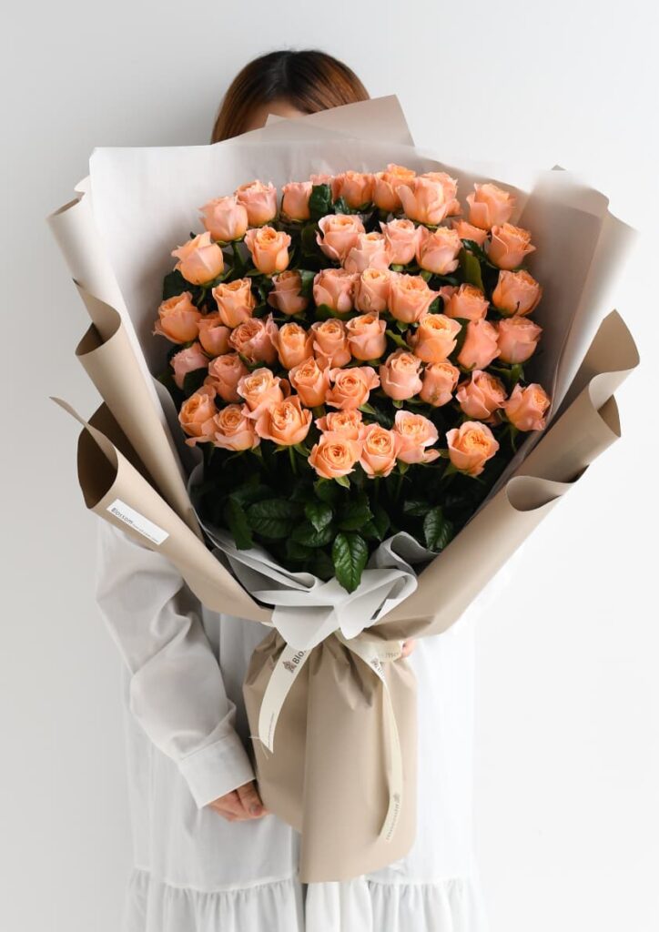 ベージュ色のラッピングをしたオレンジのバラの花束