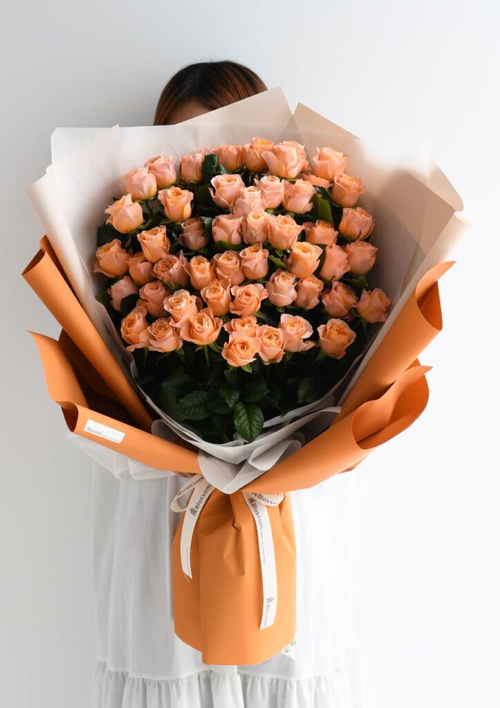 オレンジ色のラッピングをしたオレンジ色のバラの花束