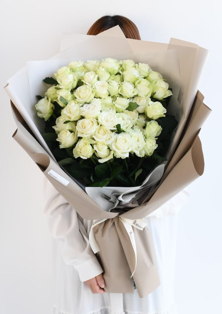 ベージュ色のラッピングをした白いバラの花束